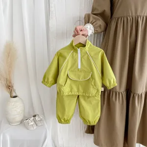 Detalle de chándal informal para niños, chaqueta cortavientos verde y pantalón colgado.