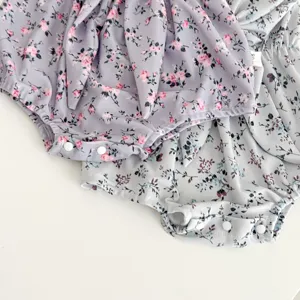 Infant floral baby romper detail view, featuring cute ruffles and convenient snap buttons.