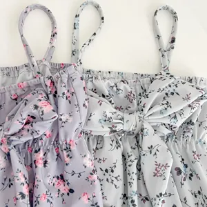 Detailed close-up view of cute baby girl floral print spaghetti strap swimsuit with a big bow.