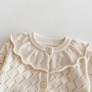 Infant baby girl knit cardigan close-up, hollow-out pattern and large ruffle collar detail.