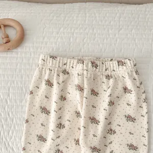 Detail shot of baby floral cotton trousers, soft texture, elastic waistband, close-up view.