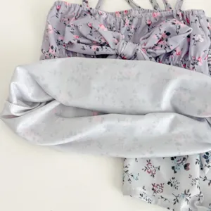 Detailed shot of cute baby girl floral swimsuit with bow strap, sweet lavender toddler bikini.