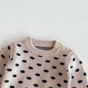 Close-up detail of infant cotton knit sweater featuring cute navy blue polka dots and shoulder buttons.