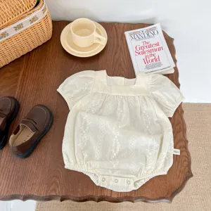 Baby girl cream embroidered short sleeve romper detail, delicate lace pattern, cute puff sleeves.