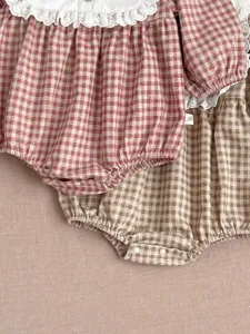 Detail shot of cute baby girl plaid romper with lace collar, showing exquisite fabric and buttons.
