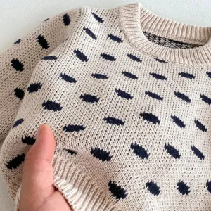 Close up view of baby knit sweater fabric texture with cute dot pattern in beige color