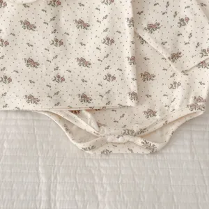 Close-up detail of infant baby floral long sleeve romper cotton fabric and snap buttons.