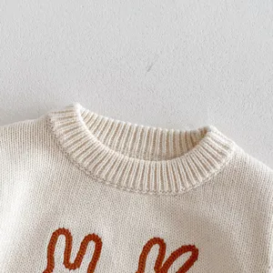 Close-up of baby knit sweater collar and cute bunny embroidery details, soft cotton yarn.