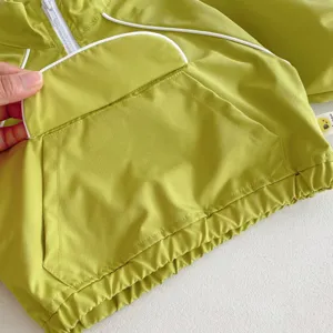 Chaqueta deportiva infantil verde claro con ribetes blancos y bolsillo con cremallera.