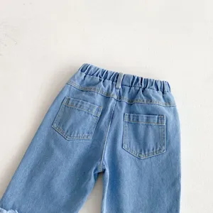 Detail shot of girls blue washed denim jeans showcasing back pockets and elastic waist.