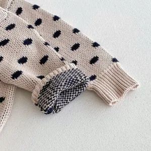 Baby knit sweater sleeve detail, cute navy dot cotton yarn knitwear closeup view.