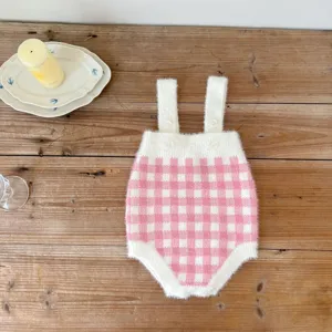 Vue détaillée de la combinaison tricotée à carreaux rose et blanc pour bébé avec bretelles.