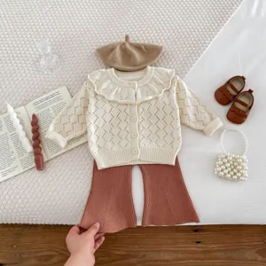 Detailed shot of baby girl knit cardigan and flared pants set with chic accessories.