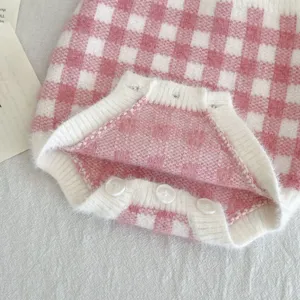 Gros plan détail barboteuse tricotée bébé rose et blanc à carreaux boutons et poignets.