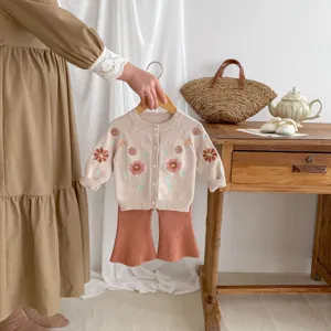 Detailed view of baby girl knitted cardigan with floral embroidery and pants set for spring.