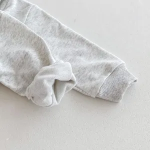 Detalle de manga de sudadera para bebé, tejido de punto gris melange suave con puños de canalé.