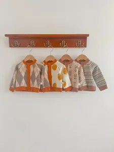 Vue détaillée de mignons gilets en tricot pour bébé sur une étagère murale en bois.