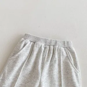 Detalle de pantalón de chándal gris para bebé, tejido suave con cintura elástica y bolsillos.