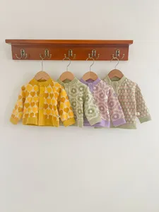 Vue détaillée de gilets tricotés pour bébé avec motifs jacquard colorés et jolis boutons.