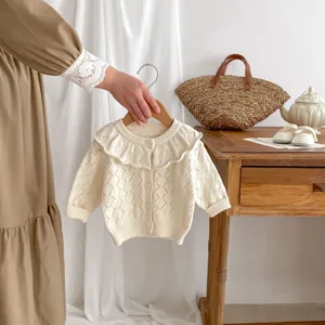 Close-up view of a baby girl knitted cardigan with hollow-out design and ruffle collar.