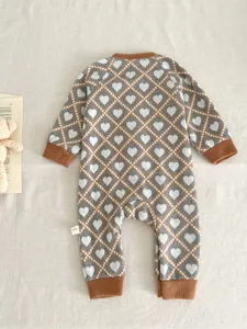 Close-up detail of the knitted baby romper with cute heart diamond pattern and brown cuffs.