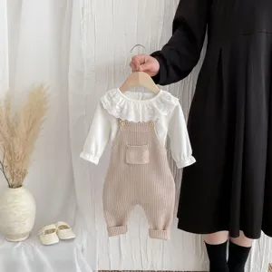 Detailaufnahme der Baby Strick-Latzhose mit weichem Stoff, niedlicher Tasche und Spitzenkragen.