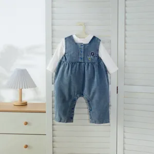 Vue détaillée de la jolie barboteuse en jean pour bébé et du haut blanc, style douillet.