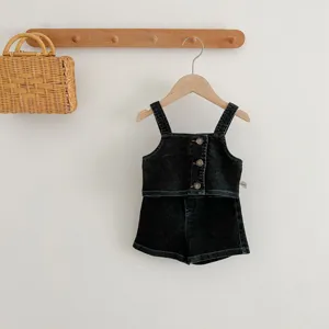 Vista dettagliata del set di jeans per bambini, top scuro e pantaloncini su appendiabiti.