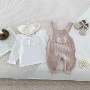 Detailansicht des Baby Strickoverall Sets im Flat-Lay-Stil mit Rüschen-Top und Beigeshorts.