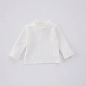 Détail du haut pour bébé en coton côtelé blanc à manches longues et col rond doux.