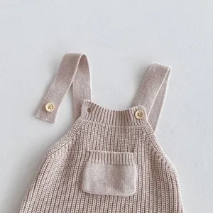 Gestrickter Baby-Strampler Detailaufnahme, süße Vordertasche und Schultergurt-Knöpfe.