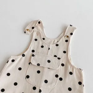 Detailed view of baby girl polka dot corduroy overalls, featuring cute front pocket and buttons.