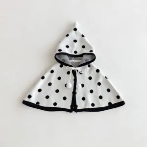 Dettaglio del mantello con cappuccio a pois per neonati con pompon e morbida maglia.