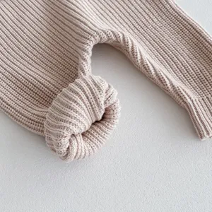 Detailaufnahme des süßen Strickstramplers für Babys in zartem Rosa mit weicher Textur.