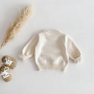 Detailed view of baby beige knit sweater, soft crewneck pullover for infants and toddlers.