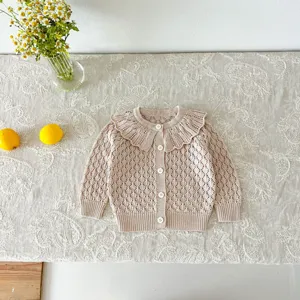 Close up detail of cute baby knitted cardigan with hollow out pattern and doll collar.