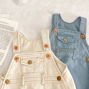 Nahaufnahme der niedlichen Baumwoll Baby Latzhosen in Creme und Blau mit feinen Knöpfen und Taschen.
