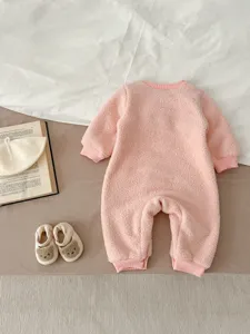 Cozy pink fuzzy baby romper detail shot with cute bear shoes and warm winter flat lay style