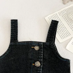 Vista dettagliata di abbigliamento in denim scuro con spalline per neonati, cuciture e bottoni blu.