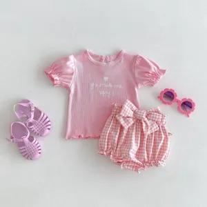 Vista dettagliata del set neonata rosa con top a costine e pantaloncini con fiocco Vichy.