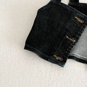 Dettaglio del gilet da neonato in denim scuro con cuciture blu e raffinata asola.