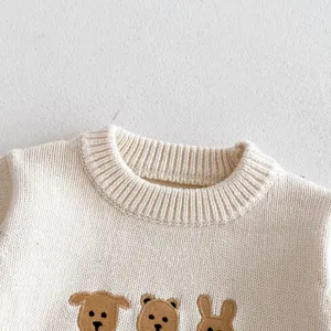 Close-up detail of baby knit sweater with cute animal embroidery, soft cream ribbed crewneck.