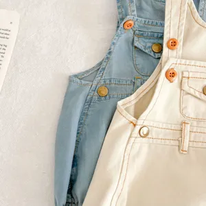 Detailansicht niedlicher Baumwoll-Baby-Latzhosen mit Trägern und Knöpfen in Blau und Beige.