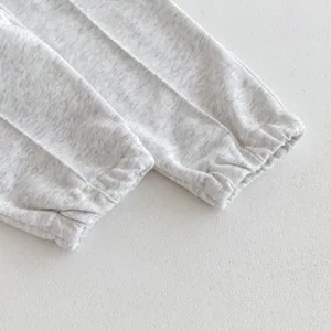 Detalle de puño de pantalón de chándal para bebé, tejido de algodón gris melange suave.