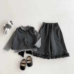 Detailed view of grey polka dot children clothing set flat lay with doll prop and shoes.