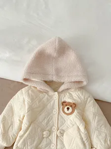 Detailed view of baby winter quilted hooded jacket with cute bear patch and soft fleece hood.