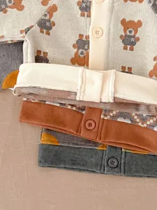 Détail gilet tricoté bébé, motif ours mignon et bord côtes, pull doux automne pour nouveau-né.