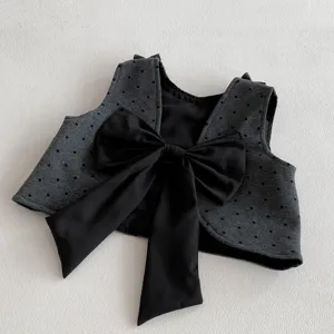 Detailed view of a stylish dark grey polka dot vest with a large black bow for girls.