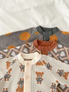 Vue détaillée de jolis gilets tricotés pour bébés avec motifs ours et géométriques.