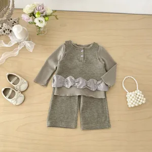 Detailed shot of baby girl waffle knit set with floral props and pearl bag on wooden table.